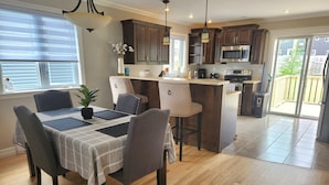 A modern kitchen with dark wooden cabinets, a central island, and a dining area with a table set for four. - *WOW!* Executive Cozy Home - 3 bedroom, 2 bath (Paradise)