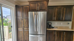 A kitchen with dark wooden cabinets, a stainless steel refrigerator, and a coffee maker on the countertop. - *WOW!* Executive Cozy Home - 3 bedroom, 2 bath (Paradise)