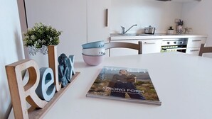 Een moderne keuken met witte kasten, een wit aanrechtblad en een tijdschrift met de titel 'STRONG FORM' op de tafel.