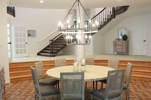 A dining area with a round table, chairs, and a chandelier.