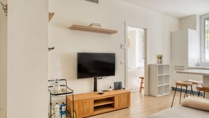 Una sala moderna con un televisor de pantalla plana, mueble de entretenimiento de madera y un carrito de vidrio con botellas.
