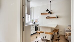 Una cocina moderna con armarios blancos, una isla central con taburetes e iluminación colgante.