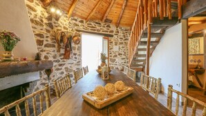A rustic dining room with a long wooden table, stone walls, and a wooden staircase. - Los Chozos Cazalla de la Sierra by Ruralidays (Seville)