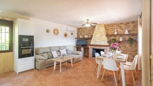 Una sala de estar con sofá, mesa de centro, televisor, chimenea y comedor.