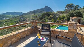 Una terraza con muros de piedra, una piscina y vistas a un paisaje montañoso.