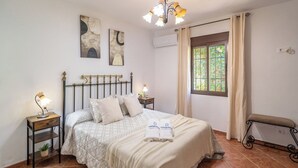 Un dormitorio con cama, mesitas de noche, una ventana con cortinas y decoración en la pared.