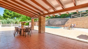 An outdoor patio with a covered seating area, stone pillars, and a swimming pool. - Casa Camino del Río Pozo Alcón by Ruralidays (Jaén)