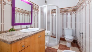 A bathroom with a granite countertop, a white sink, a mirror, a shower enclosure, and a toilet. - Casa Camino del Río Pozo Alcón by Ruralidays (Jaén)