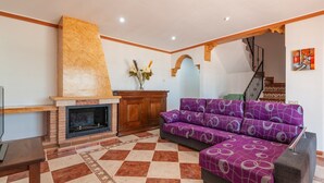 A living room with a fireplace, a sofa, and a staircase. - Casa Camino del Río Pozo Alcón by Ruralidays (Jaén)