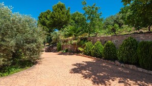 A paved pathway leading through a landscaped garden with various trees and shrubs. - Casa Camino del Río Pozo Alcón by Ruralidays (Jaén)