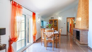 A spacious living area with a fireplace, a dining table, and a kitchen in the background. - Casa Camino del Río Pozo Alcón by Ruralidays (Jaén)