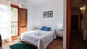 A bedroom with a bed, two bedside tables, a window with curtains, and a door.