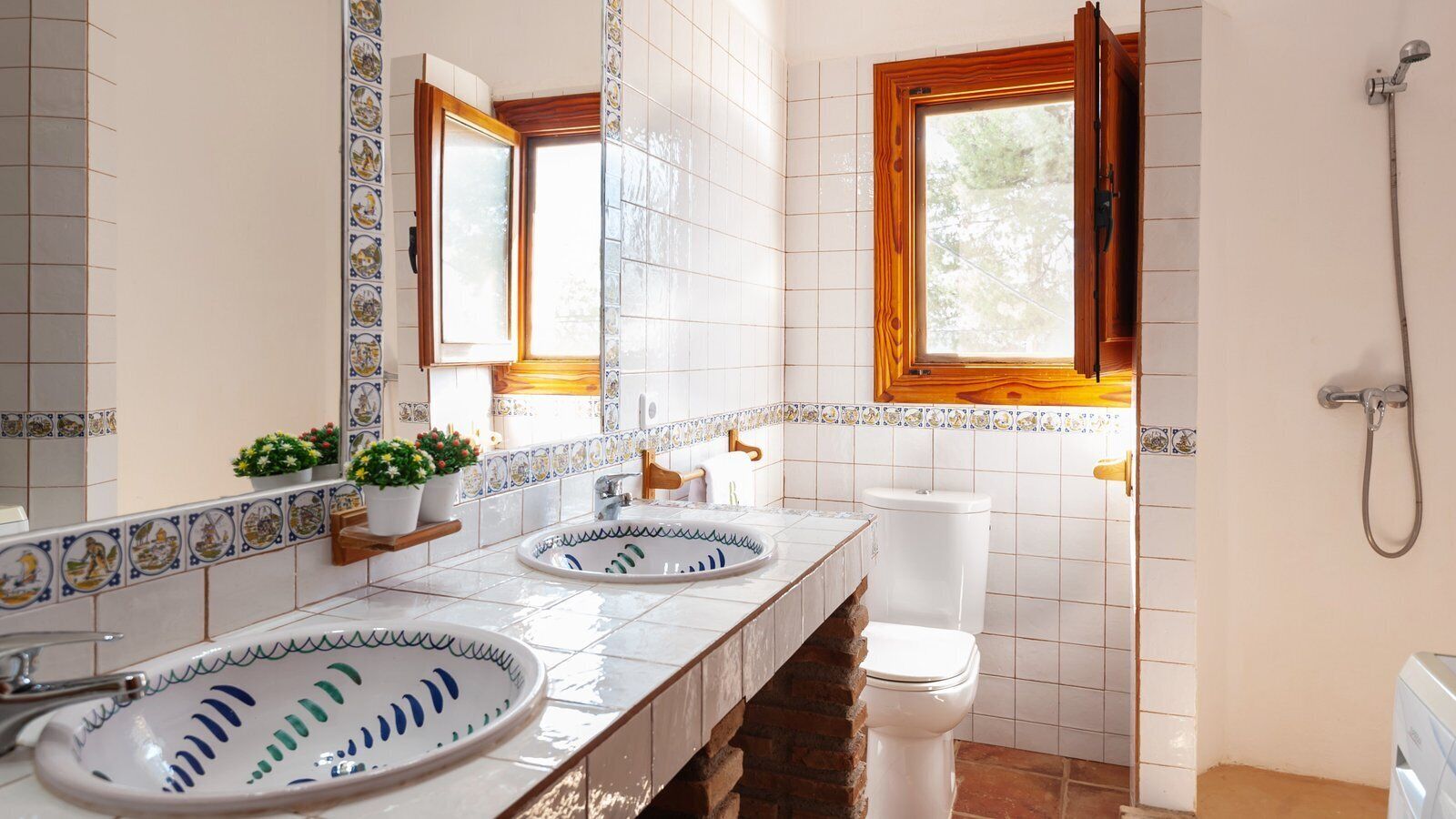 Un baño con dos lavamanos, un inodoro, una ducha y una ventana.