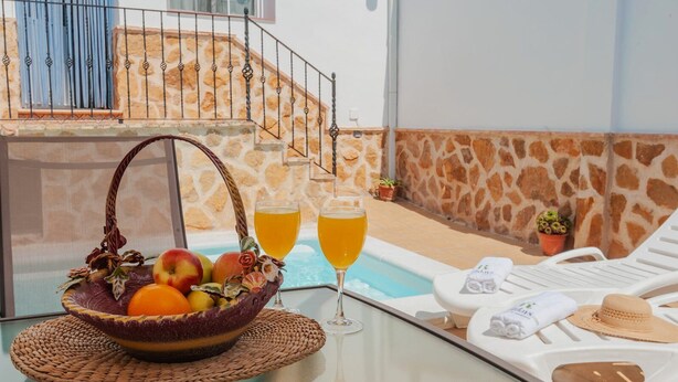 Ein Poolbereich mit einem Korbwäscher voller Früchten, zwei Orangensäften und einer weißen Liege mit Handtüchern.