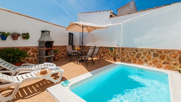 Ein Poolbereich mit Liegestühlen, einem Grill und einem Tisch mit Stühlen.