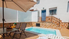 Ein Poolbereich mit Tisch, Stühlen und einer Liege.