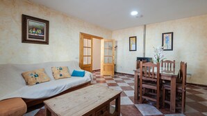 Ein Wohnzimmer mit einer Couch, einem Holztisch und einem Essbereich mit Stühlen.