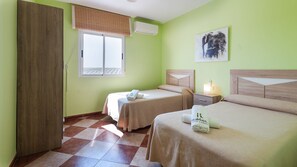 Ein Hotelzimmer mit zwei Betten, einem Fenster mit Jalousien, einem Bild an der Wand und einem Holzschrank.