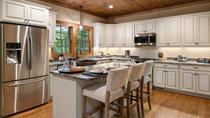 Una cucina moderna con mobili bianchi, elettrodomestici in acciaio inossidabile e soffitto in legno.
