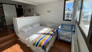 Een slaapkamer met een bed, een raam, een radiator en een blauwe stoel.