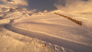 Een besneeuwd landschap met een houten omheining en een kronkelend pad.