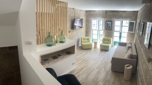 Een moderne woonkamer met een stenen muur, een tv boven een open haard en een zithoek.