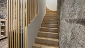 Een houten trap met modern ontwerp, die leidt naar een kamer met een stenen muur en een plank met servies.