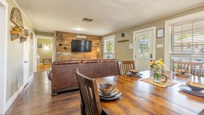 A dining area with a wooden table, chairs, and a television mounted on a wooden wall.