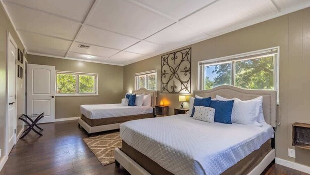A bedroom with two beds, a large window, and a decorative wall piece.