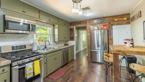 A kitchen with stainless steel appliances, a wooden dining table, and a view of the outdoors.