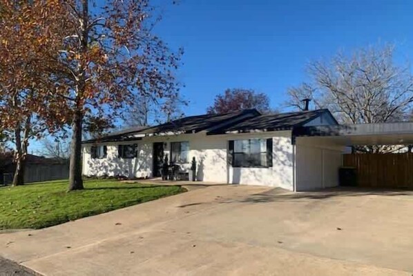 A single-story house with a sloped roof, a front porch, and a garage. - Bayer Guest Haus-hot Tub and Fire Pit (Fredericksburg)