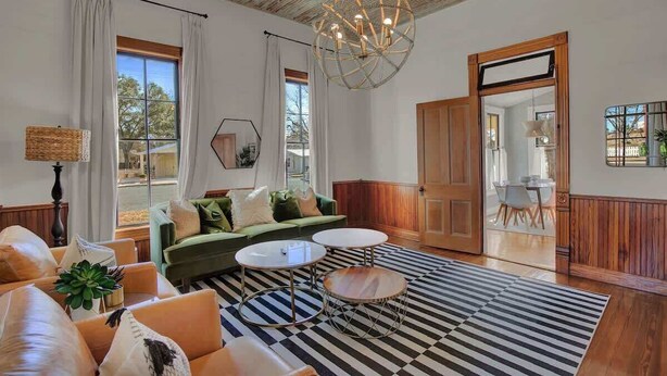 A spacious living room with a green sofa, two round tables, and a black and white striped rug. - Gorgeous Home 1 Blk From Main With Hot Tub & Fire Pit! (Fredericksburg)