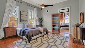 A bedroom with a bed, a ceiling fan, a window with curtains, a bedside table, and a dresser. - Gorgeous Home 1 Blk From Main With Hot Tub & Fire Pit! (Fredericksburg)