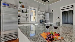 A modern kitchen with a granite countertop, stainless steel appliances, and a fruit platter. - Gorgeous Home 1 Blk From Main With Hot Tub & Fire Pit! (Fredericksburg)