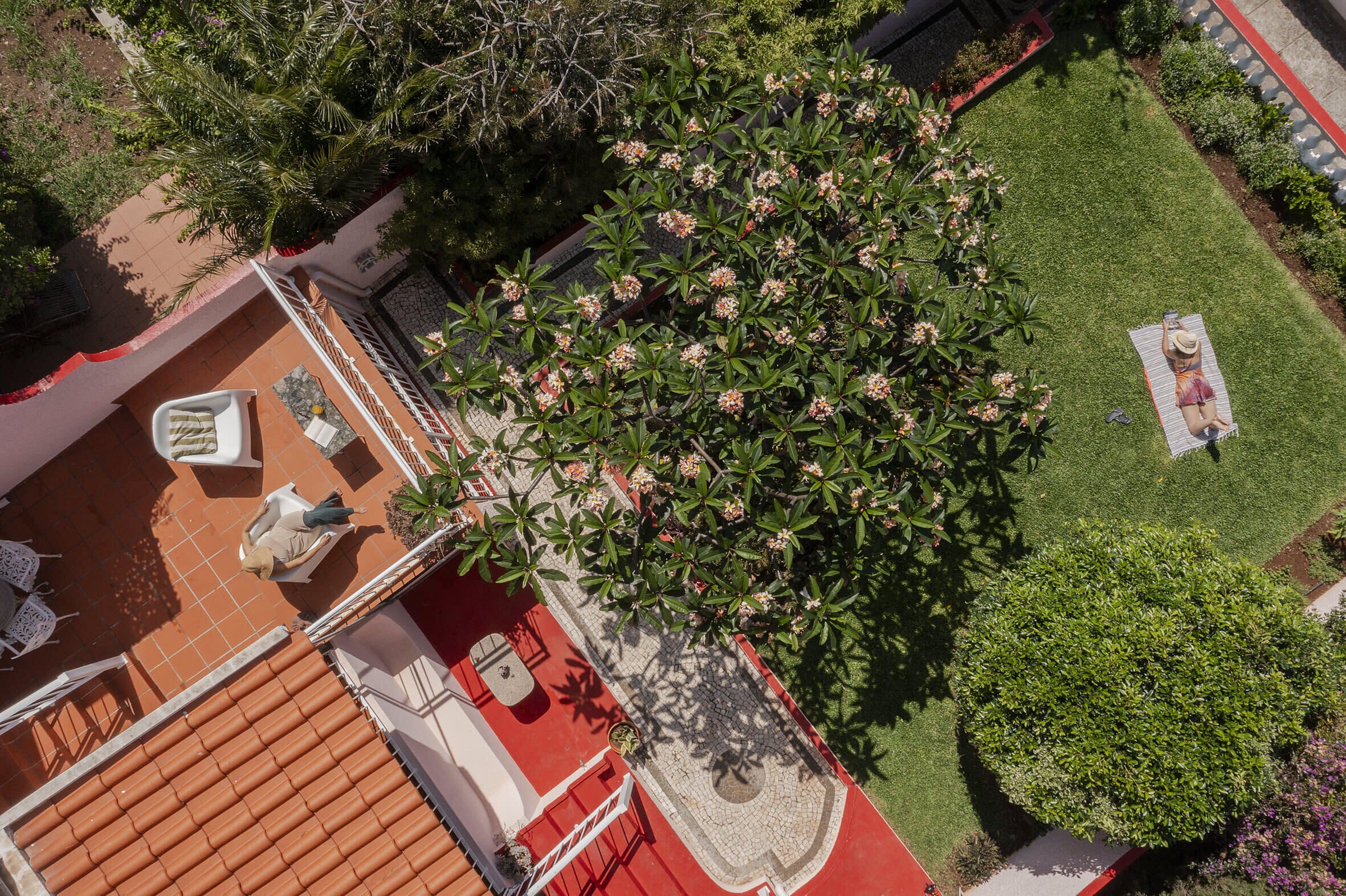 An aerial view of a courtyard with a tiled patio, a small seating area, and a well-maintained lawn.