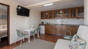 Ein kompakter Wohnbereich mit Küchenzeile, Essbereich und Wand-Fernseher.