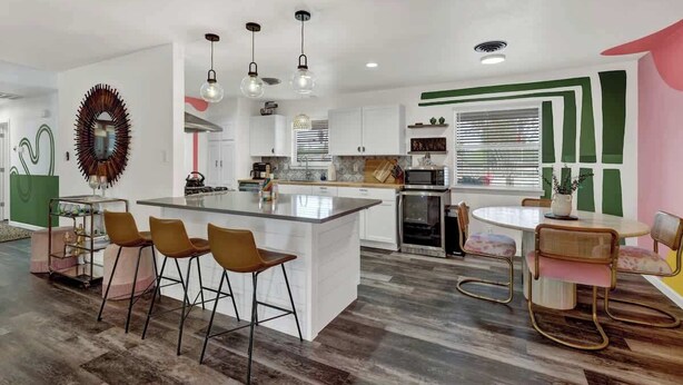 A modern kitchen with a central island, bar stools, and pendant lighting. - Eclectic Fun Haus With Hot Tub - 3 Min Drive to Main (Fredericksburg)