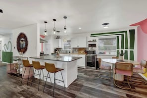 A modern kitchen with a central island, bar stools, and pendant lighting.