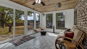 A spacious room with large windows, a ceiling fan, and a patterned floor. - Eclectic Fun Haus With Hot Tub - 3 Min Drive to Main (Fredericksburg)