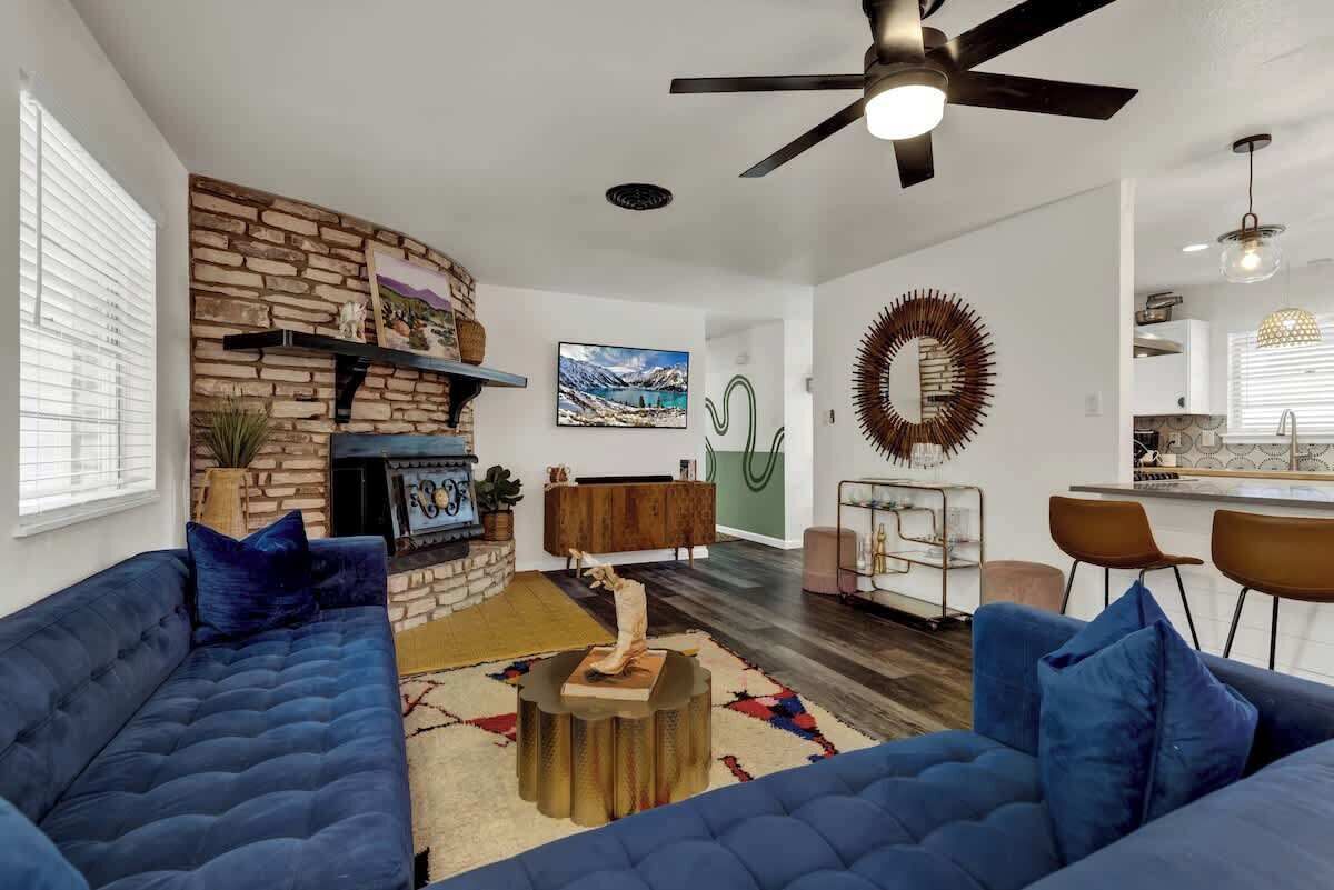 Una sala moderna con chimenea de piedra, sofás azules y un comedor con taburetes de bar.