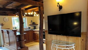 Une cuisine moderne avec des meubles en bois, un grand téléviseur à écran plat et une table à plateau en verre.