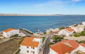 Ein Küstenwohngebiet mit weißen Gebäuden, roten Ziegeldächern und freiem Blick auf das Meer.