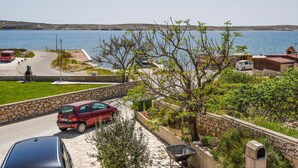 Eine Küstenstraße mit parkenden Autos, einer Steinmauer und Blick aufs Meer.