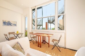 A bright living room with a large window, a wooden table, and a white sofa.