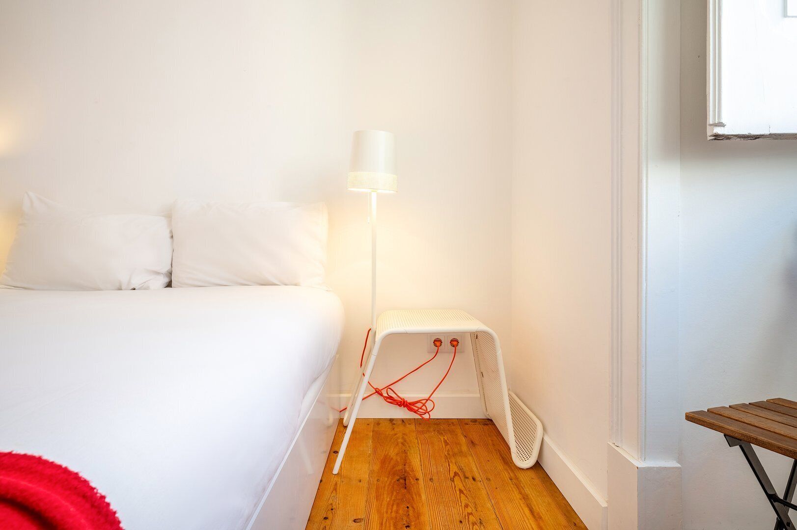A bedroom with a bed, a standing heater, and a wooden floor.