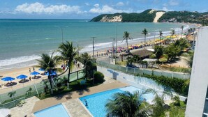 Un resort en la playa con piscina, sombrillas y vistas al océano.