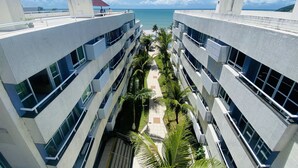 Un hotel moderno con un patio central, varios balcones y vista al océano.