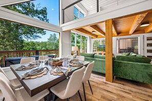 A spacious outdoor dining area with a wooden table set for four, surrounded by white chairs.