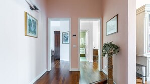 A hallway with hardwood floors, framed artwork, a large mirror, and a potted plant. - GuestHost - Elegant apartment of 80 sqm, able to accommodate up to 5 people, located on the 2nd floor of a building equipped with a lift (NOT suitable for disabled people - some steps to access). The property is located in the Stibbert/Statuto area, a li (Firenze)
