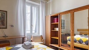 A hotel room with a bed, a chair, a desk, a wardrobe, and a window with curtains. - GuestHost - Elegant apartment of 80 sqm, able to accommodate up to 5 people, located on the 2nd floor of a building equipped with a lift (NOT suitable for disabled people - some steps to access). The property is located in the Stibbert/Statuto area, a li (Firenze)